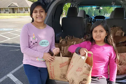 Two children holding grocery bags outside the Center for Community Transitions sober living home in Charlotte.